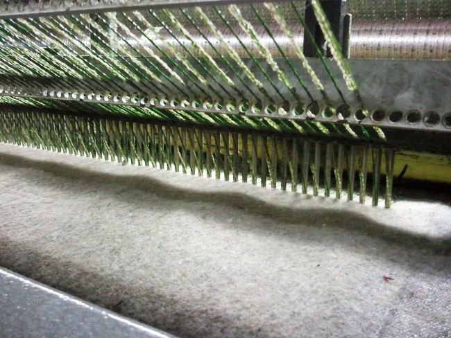 Comme dans l'industrie textile, l'herbe artificielle est piquée sur une trame tissée